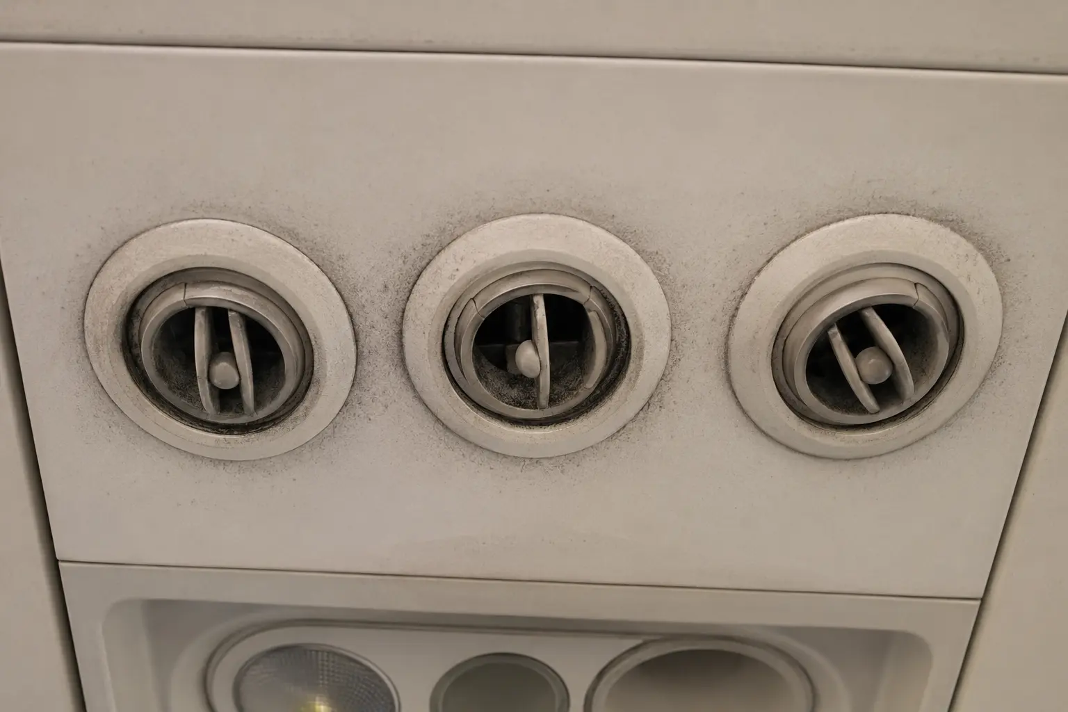Illustrative aircraft overhead panel showing visible dark buildup around the air vents